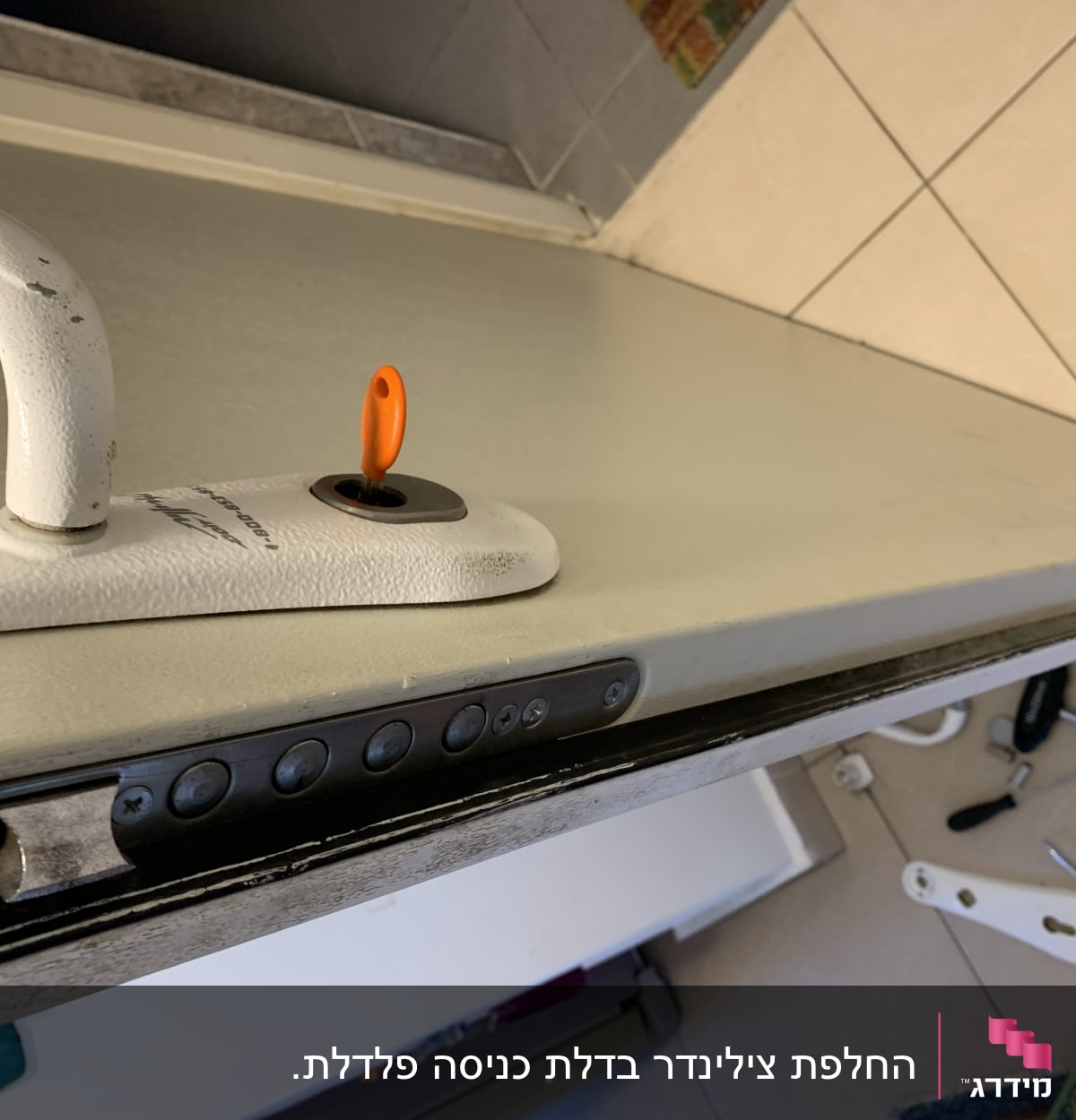 ידית דלת עם מפתח כתום וכלי עבודה על הרצפה